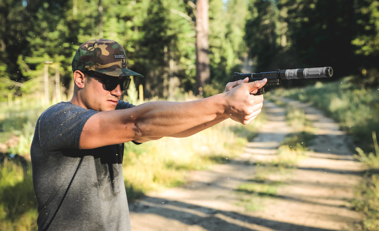 man shooting pistol with switchback 22, outdoors in the woods just off a path