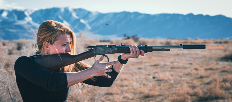 woman shooting .22lr lever action rifle with rimfire suppressor