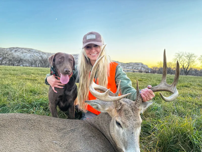 Bridget Fabel and chocolate lab named Dixie with a Whitetail buck she harvested with a rifle suppressed with the Silencerco Scythe-Ti suppressor